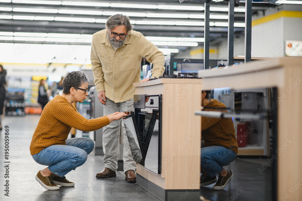 Fototapeta premium Mature couple choosing new built in oven in appliance store