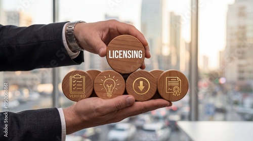 Businessman holding wooden blocks with licensing text and icons for business strategy management and legal rights conceptual development in a modern bright office environment with blurred city