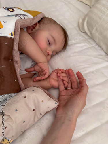 Peaceful sleeping baby holding adult hand Close Up