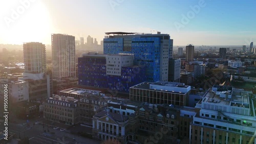 An aerial approach towards a modern hospital building with the sun rising over the city skyline.