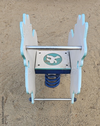 Spring rider playground equipment isolated on sand background