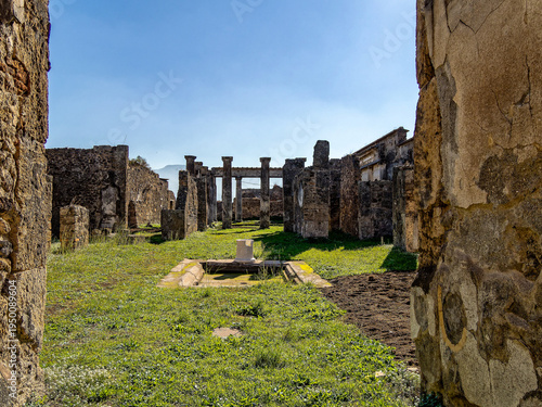 фотографія Lush peristyle in Pompeii Roman villa with central rainwater pool amid columns and grass, dramatic Mount Vesuvius looming behind ancient ruins