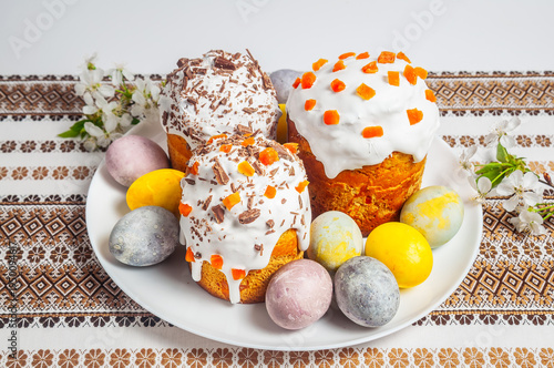 Traditional Easter cakes and painted eggs arranged on a festive tablecloth with spring blossoms