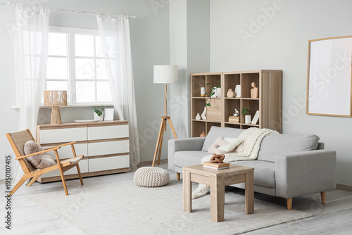 Interior of stylish living room with grey sofa, armchair and commode