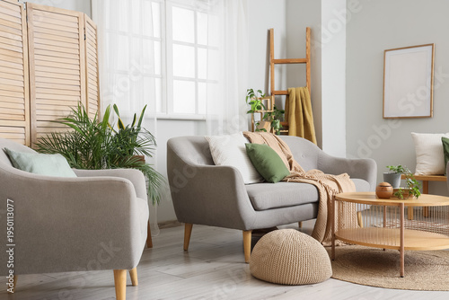 Interior of light living room with window, sofa and armchair