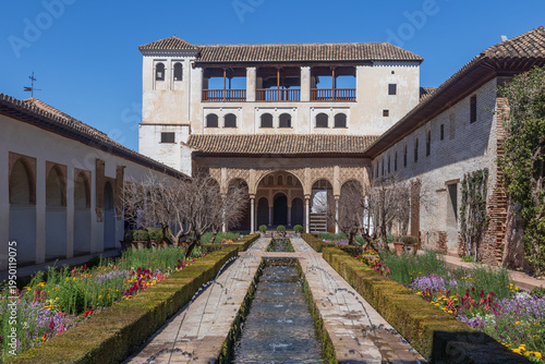 El Generalife: Jardines y agua del paraíso. Un encuadre simétrico del Patio de la Acequia, mostrando los surtidores de agua, las flores de primavera y la arquitectura del palacio de verano.