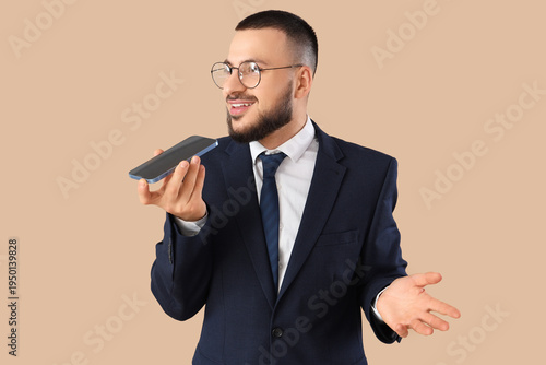 Young businessman using mobile phone on beige background. Search concept