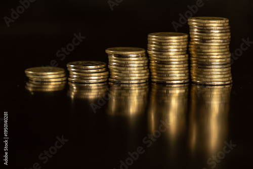 Stacked coins show increasing value on a dark surface during the day