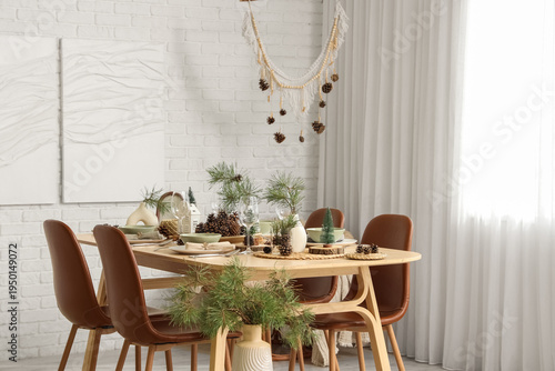 Interior of room with dining table, fir branches and paintings
