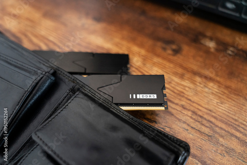 Photos Black DDR5 RAM memory modules placed inside a black wallet on wooden surface
