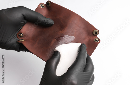 Fotografija Tanner applies cream to a leather organizer on white background