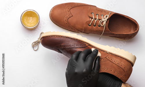 Shoemaker applies shoe polish to leather shoes on a white background