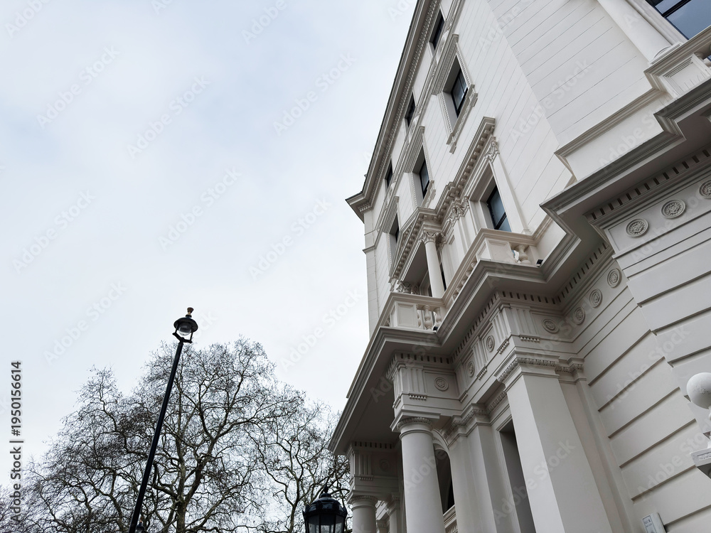 Fototapeta premium Elegant white building with ornate columns in London, featuring a street lamp and bare trees