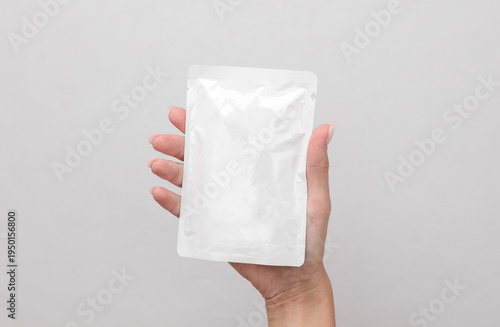Foto Hand holding Mockup of a white package or pouch of liquid cat food on gray backg