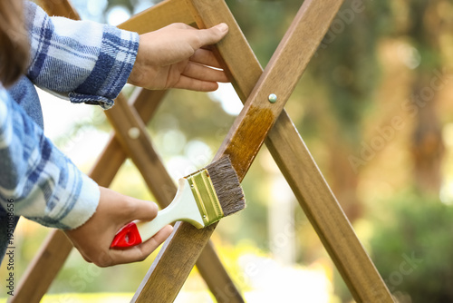 Bild auf Leinwand Woman painting wooden table in garden, closeup