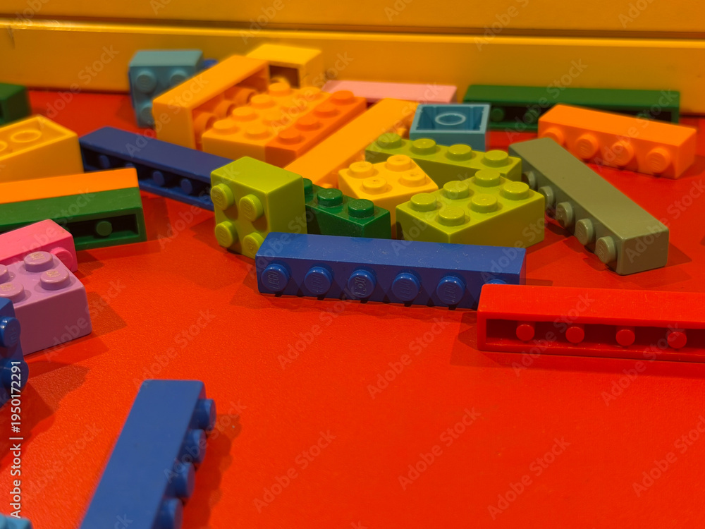 Fototapeta premium Colorful toy building blocks on red surface
