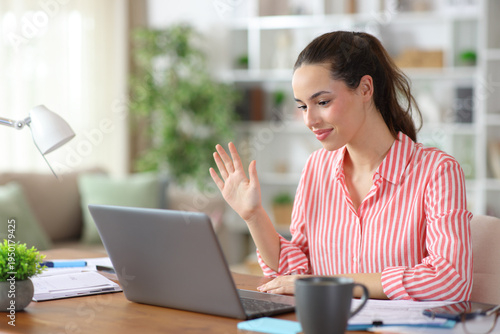 Foto Self employed making video call using laptop working at home