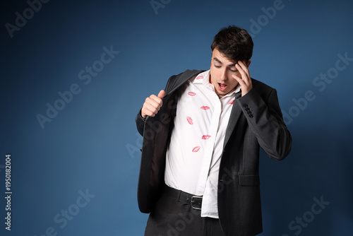 Photography Shocked man with kiss marks on his shirt against dark blue background