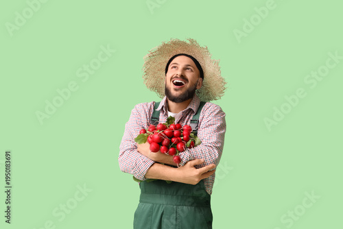 Happy male farmer with ripe radish on green background