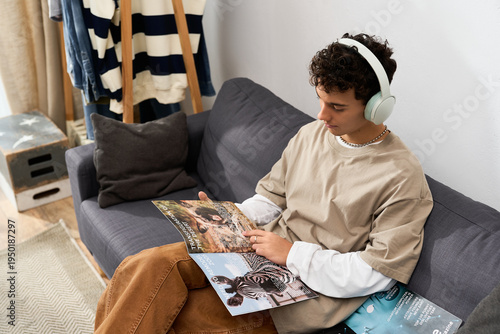 Fényképezés Stylish teenager enjoying quiet moments at home while reading interesting magazi
