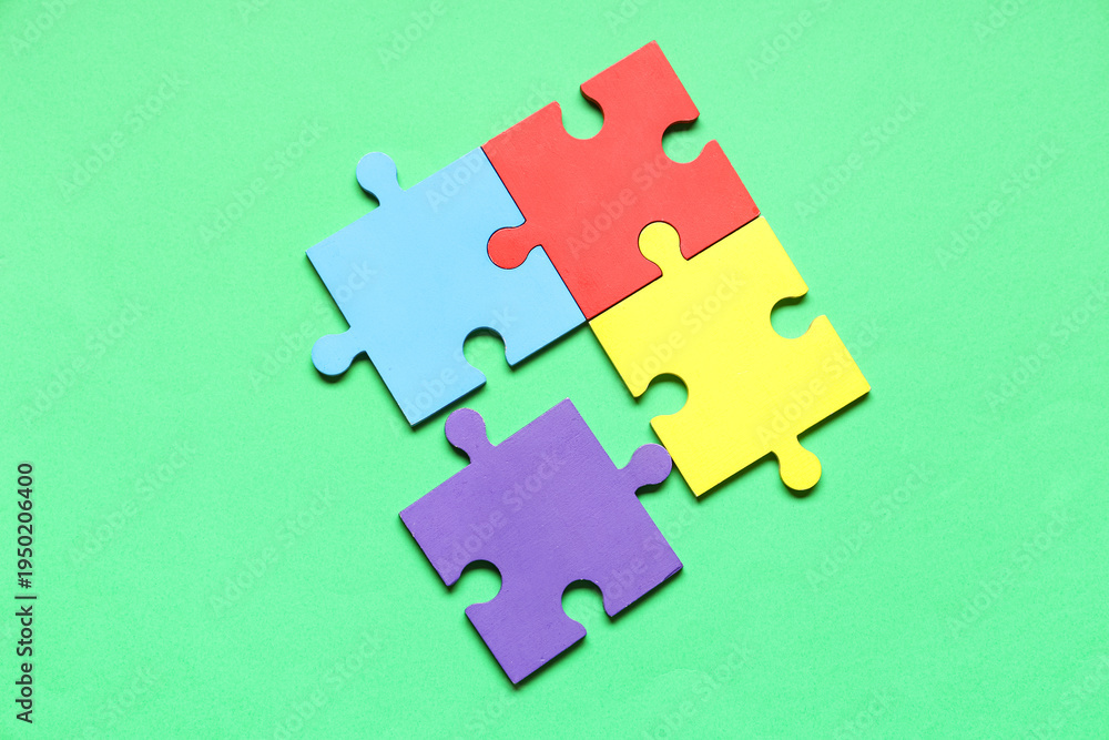 Fototapeta premium Colorful puzzle pieces on green background. Autistic disorder concept
