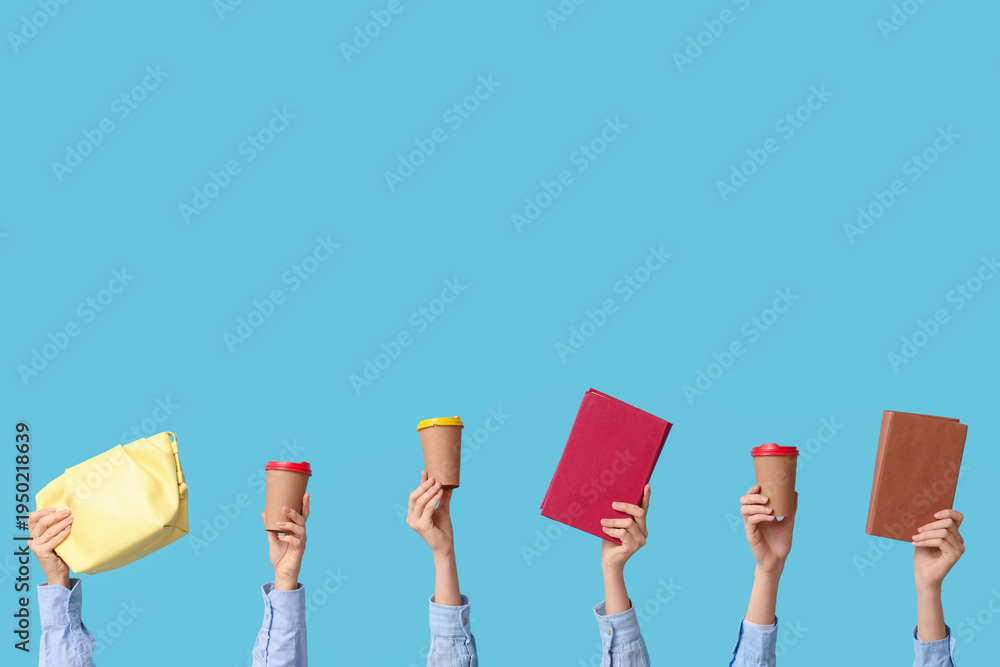 Fototapeta premium Female hands with books, bag and paper cups of coffee on blue background