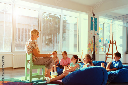 Teacher reading a story to attentive children during cozy classroom story time in a bright kindergarten