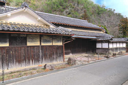 日本の原風景：田舎の静かな道と古い橋、伝統的な家屋が並ぶノスタルジックな風景