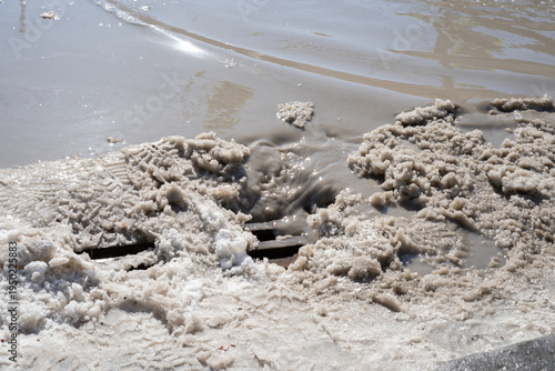 Konstfotografi Mud and foam buildup near surface of riverbank in sunlight