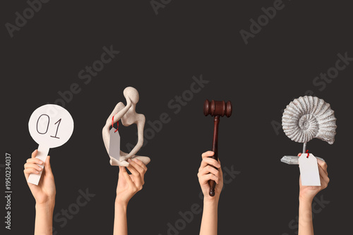 Tableau sur toile Female hands with auction paddle, gavel and antique items on dark background