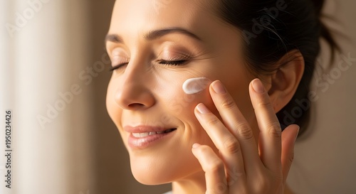 Mature woman gently applies nourishing cream to her cheek with her fingers
