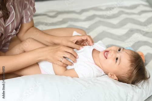 Mother tickling her little ...