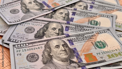 Fotografie Fan of US hundred dollar bills on a natural cracked tree stump