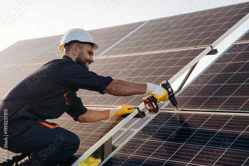 Wallpaper Mural Yellow drill is in hands, installation process. Male solar engineer examining photovoltaic panels at a power station Torontodigital.ca