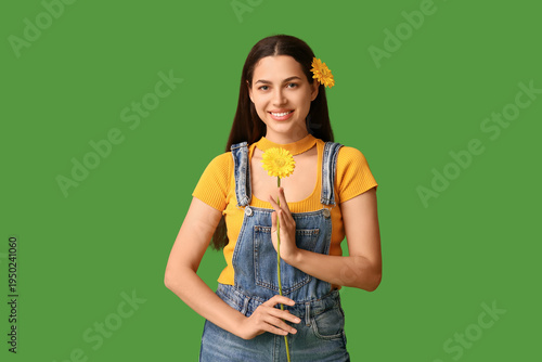 Beautiful young happy woman with chrysanthemum flowers on green background