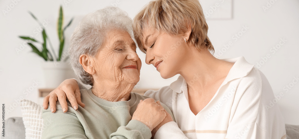 Obraz premium Mature woman with her mother hugging on sofa at home
