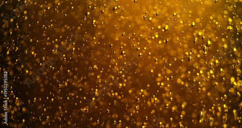 Abstract golden bubbles rising in liquid with sparkling highlights and soft bokeh. Macro texture resembling carbonation in beer, champagne or sparkling beverage creating a luxurious glowing backgrou