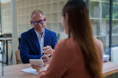 Foto Experienced businessman smiling discussing investments with client