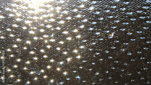 Schilderij op canvas Sparkling sun glints reflecting off a textured rain or seedy glass bubble style surface