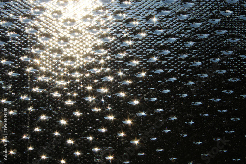 Foto Sun sparkles off a textured seedy glass surface