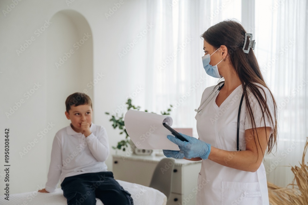 Fototapeta premium Writing notes into notepad. Boy is in routine appointment in clinic with female doctor
