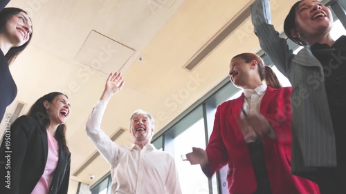 Diverse group of business professionals placing hands together in team unity gesture during meeting in modern office.