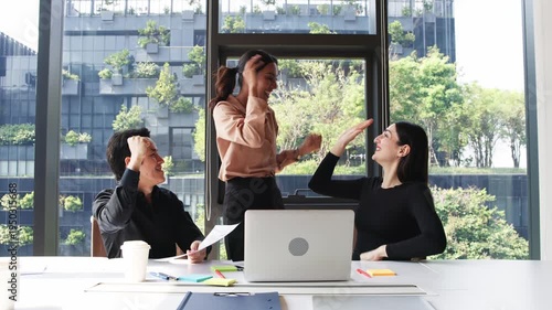 Three business professionals discussing charts and reports while analyzing information on laptop during collaborative office meeting.