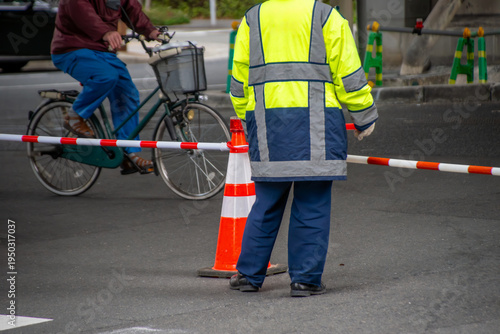 道路工事で通行規制された大通りを見守る交通誘導員