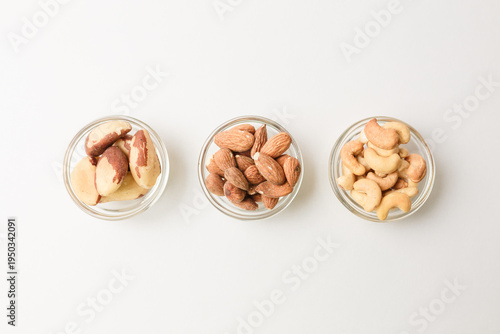 Three bowls with Cashew, almond and Brazil nuts on white background. Copy space