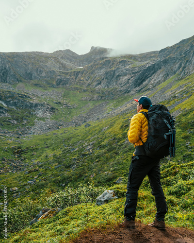 Man with backpack from behind with mountain background in Nordic Norway