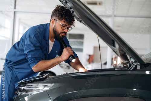 Wallpaper Mural With flashlight in hand. Auto service specialist examining vehicle condition Torontodigital.ca