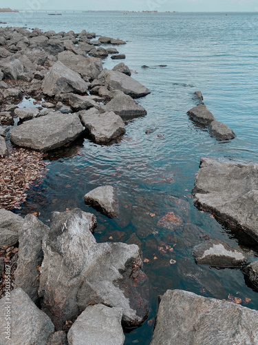 rocky terrain with stones against the backdrop of a seashore with blue water and waves
