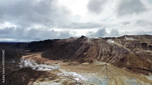 Aerial drone view of steaming fumaroles and sulfur vents in the Hverir geothermal area near Namafjall. White steam rises from mineral stained earth in an otherworldly volcanic environment
