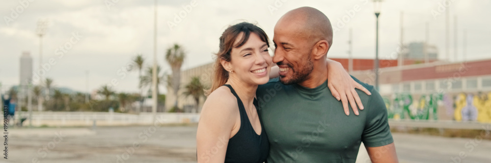 Fototapeta premium Close up of young cheerful couple in love strolling along the waterfront in the morning. A pleasant conversation with joy, a couple walking and cuddling. Couple goals. Panoramic